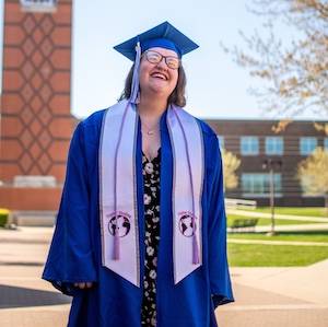 Randee Gage in cap and gown in front of the GVSU clock tower